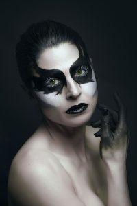 In this stunning portrait, a model with porcelain white skin and bold black and white makeup is captured in an artistic and striking image. The use of monochromatic tones highlights the model's features and adds a dramatic effect to the composition. The contrast between the light skin and the dark makeup creates a sense of depth and adds a layer of complexity to the image. With this captivating photograph, the photographer skillfully captures the model's unique beauty and individuality, while showcasing their expertise in portraiture and fashion photography.