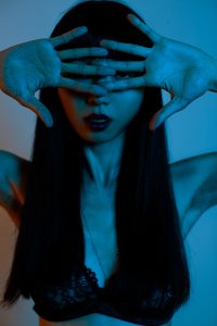 A stunning woman poses with her eyes covered by the back of her fingers, surrounded by a dynamic blue light setting. The use of color and creative lighting techniques helps to add drama and depth to the image, while also emphasizing the model's beauty and poise. With the careful use of bokeh and attention to detail, this portrait captures the model's unique personality and style, making it a true work of art. As a talented commercial and portrait photographer based in Nashville, Paris, and Tokyo, Foto Timo has a keen eye for capturing compelling and visually stunning images like this one.